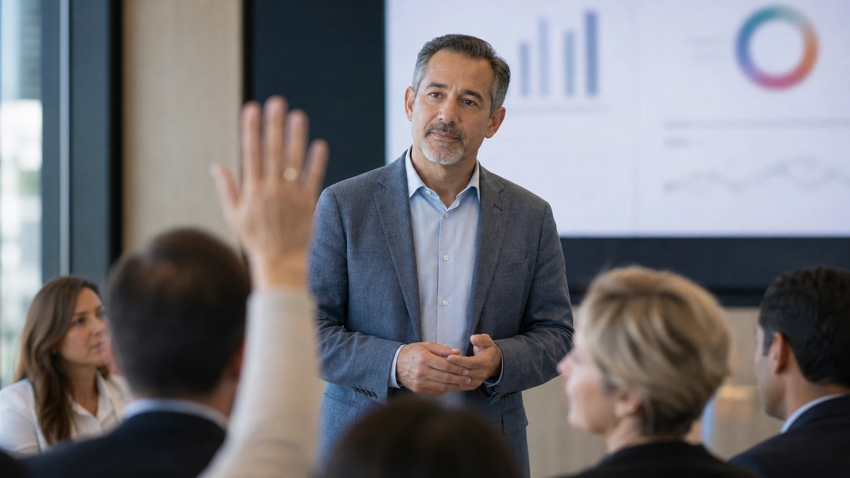 An audience member raising a question while a presenter listens from the front of the room