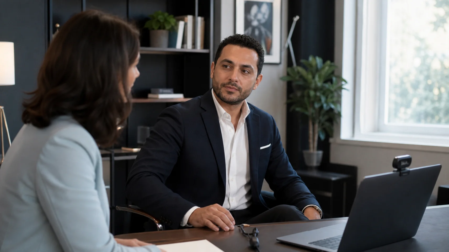 An executive at his desk preparing for a remote media interview with a coach beside him