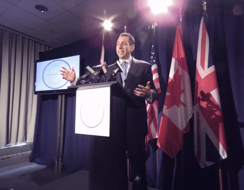 Jess Todtfeld speaking at the United Nations, at a lectern lined with microphones